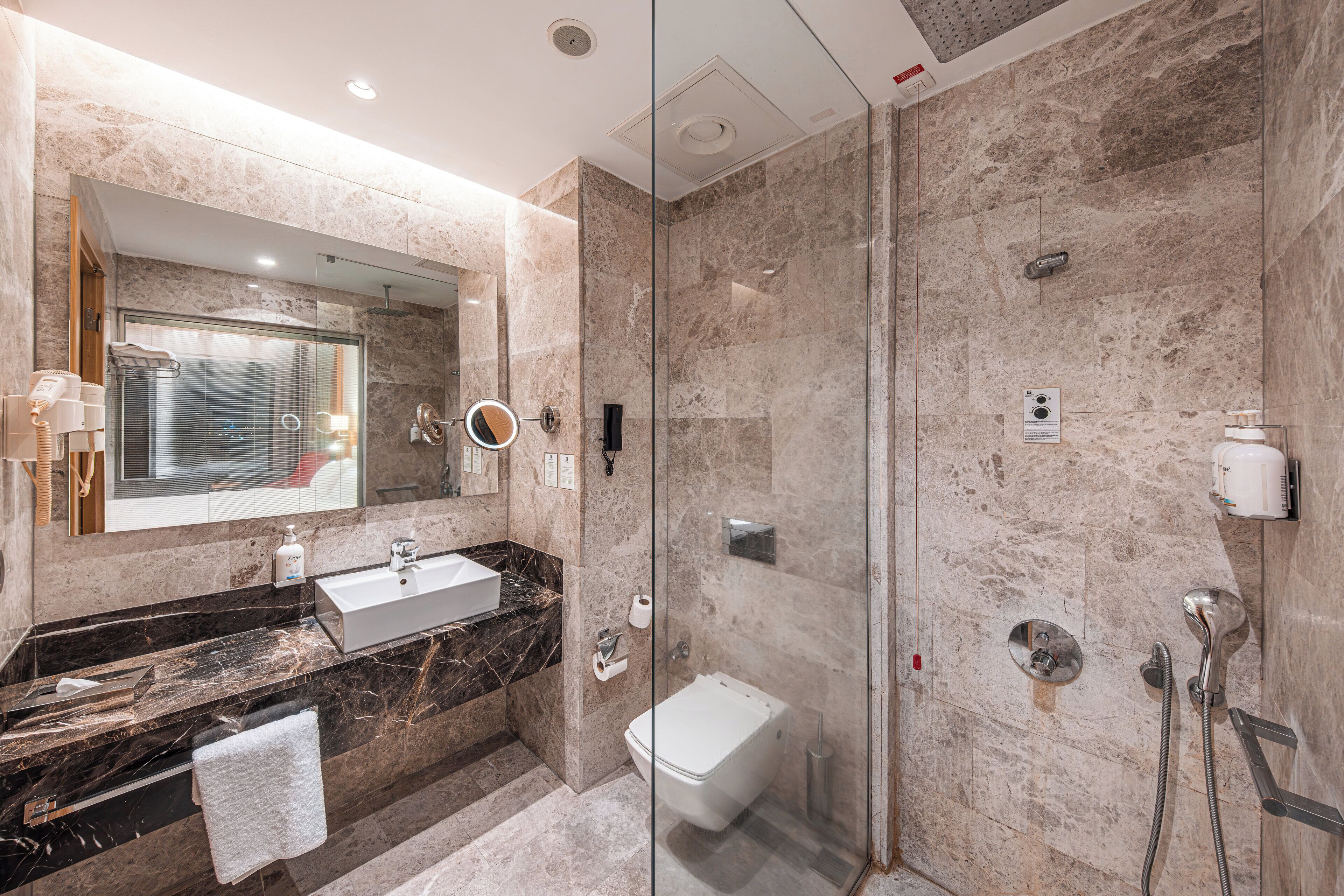 A modern bathroom with a glass-enclosed shower, a marble sink, and a large mirror.