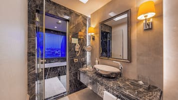 Un baño moderno con ducha de vidrio, un espejo grande y encimera de mármol.
