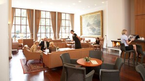 A spacious hotel lobby with comfortable seating areas, a fireplace, and large windows. - Palais Esplanade Hamburg - Adults Only (Hamburg)