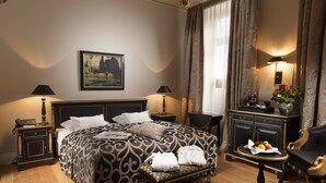 A hotel room with a large bed, two bedside tables with lamps, a chair, a small table with a vase of flowers, and a painting on the wall. - Palais Esplanade Hamburg - Adults Only (Hamburg)