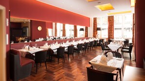 A restaurant with long tables, red walls, and wooden flooring. - Palais Esplanade Hamburg - Adults Only (Hamburg)