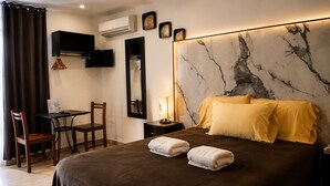 A hotel room with a bed, a desk, a chair, a TV, and an air conditioner. - Finca Chipitlán Hotel (Cuernavaca)