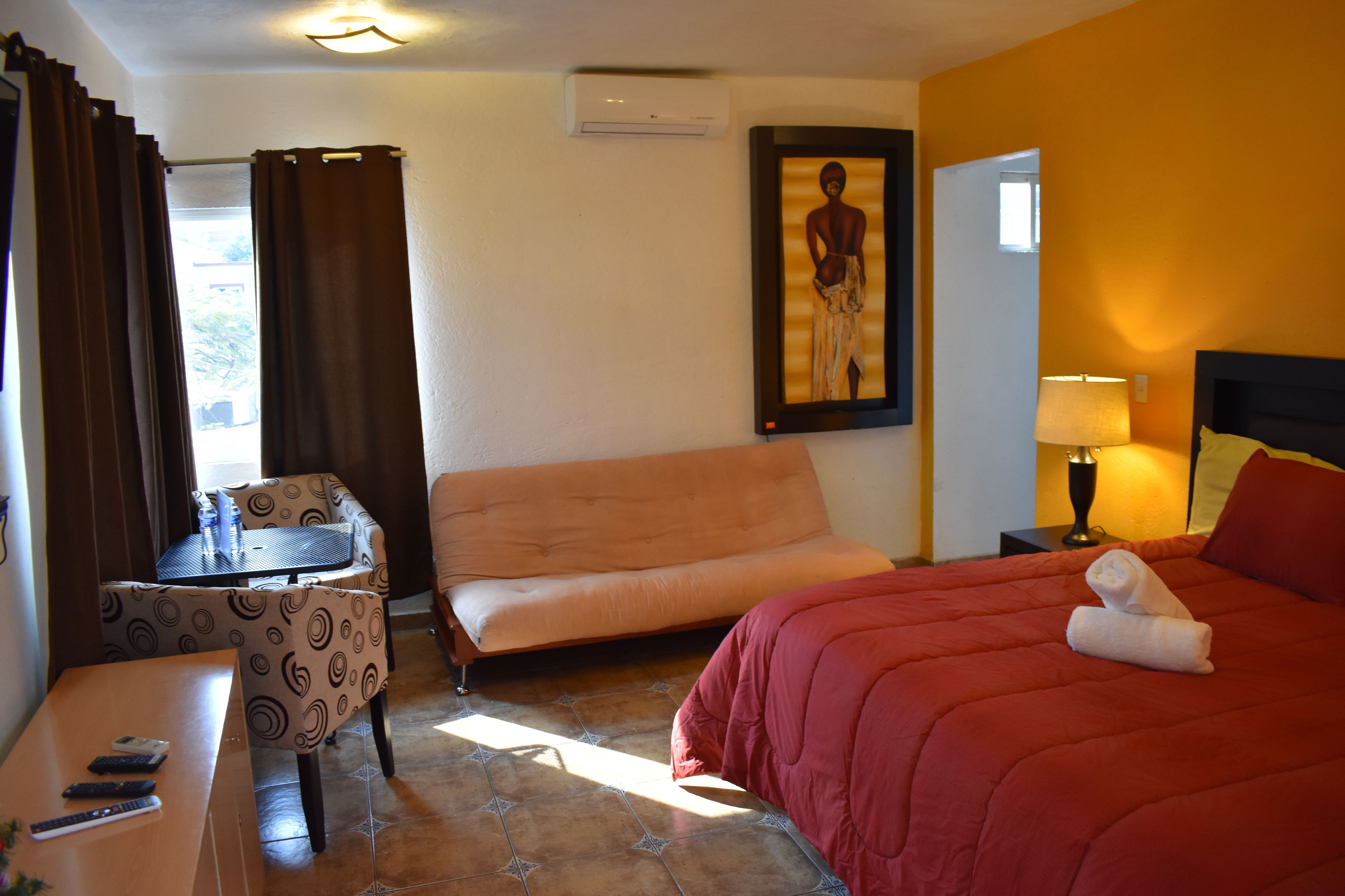 Una habitación de hotel con una cama, un sofá, una mesita y una silla.