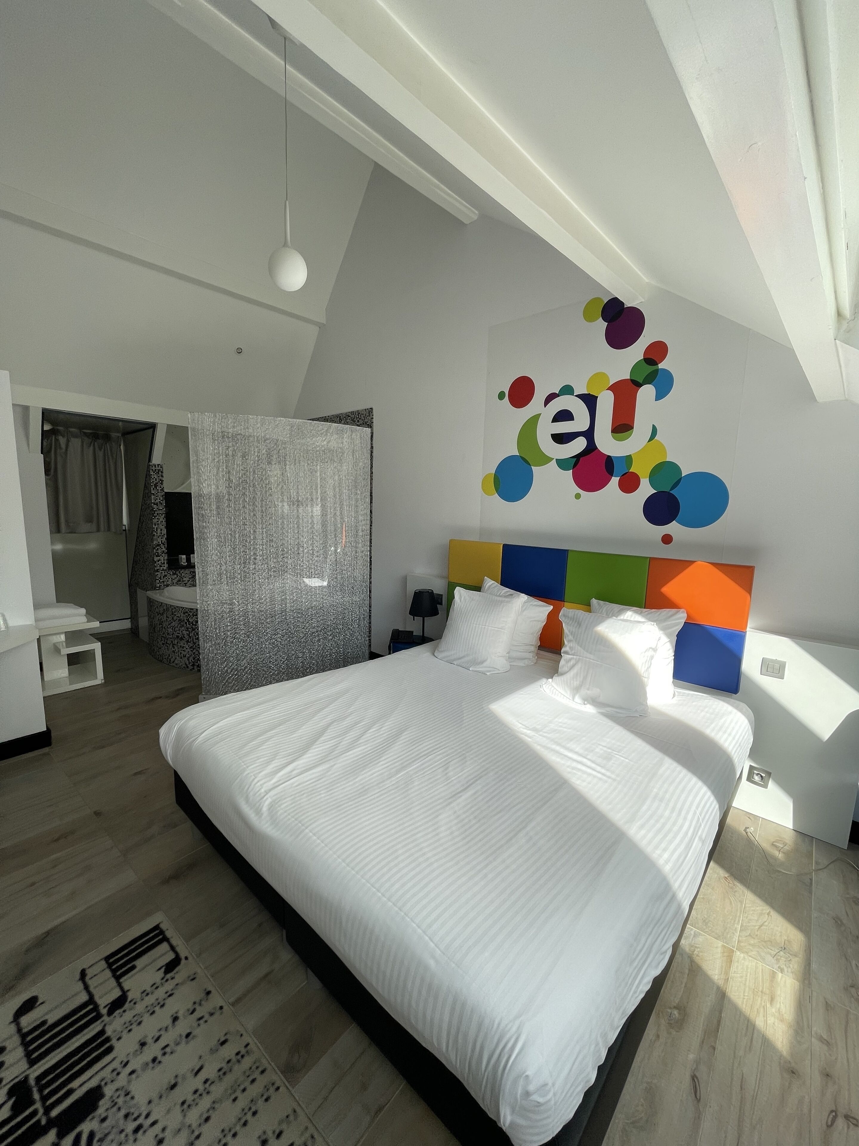 Ein modernes Schlafzimmer mit einem großen Bett, einem farbenfrohen Wandbild und einem Oberlicht.