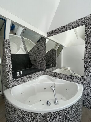 A modern bathroom with a large freestanding bathtub, a mirrored vanity, and mosaic tile walls. - Martin’s Dream Hotel (Mons)