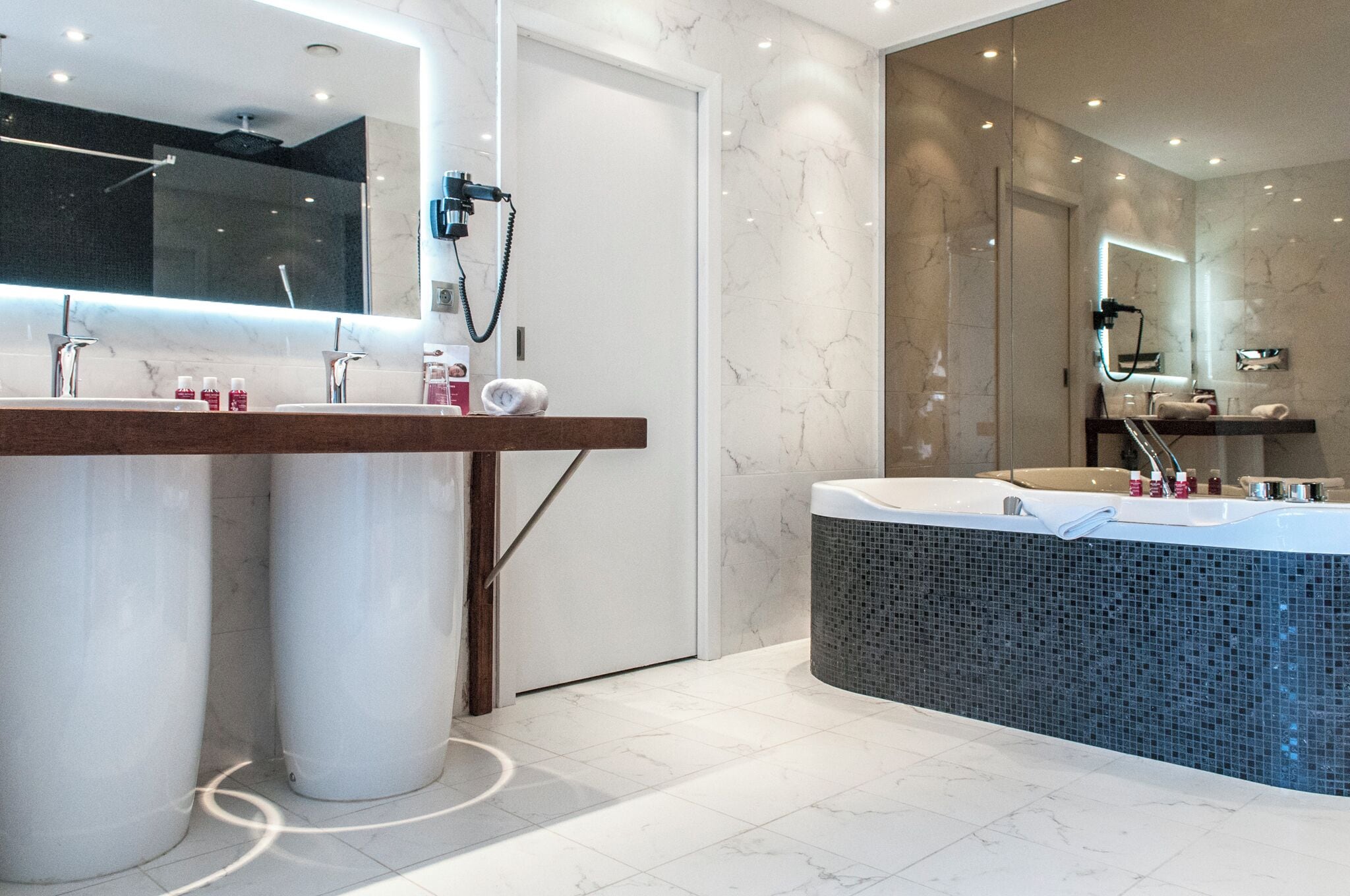 Une salle de bain moderne avec deux lavabos, un grand miroir et un espace séparé pour la baignoire.
