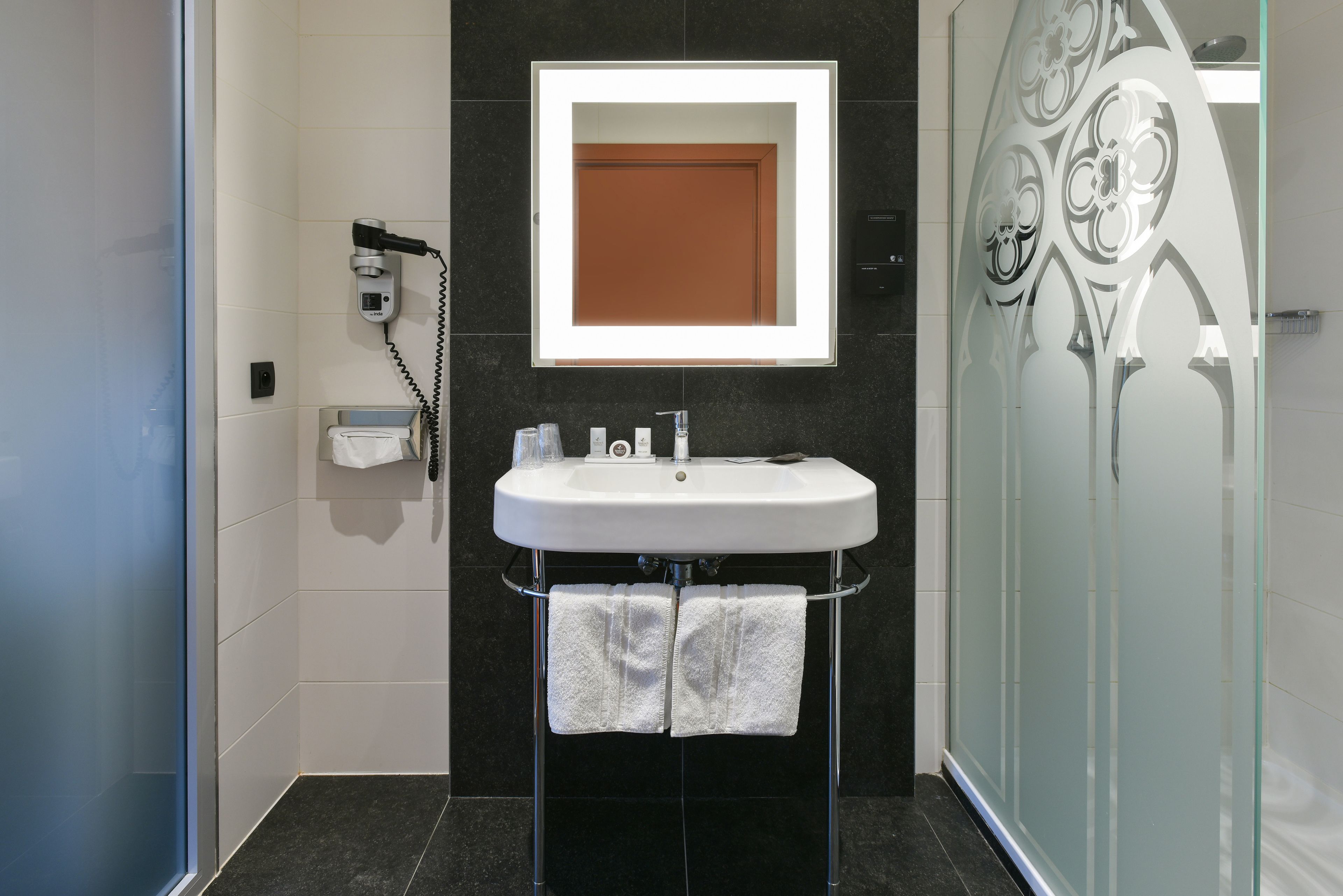 A modern bathroom with a white sink, a mirror, and a shower enclosure.