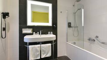A modern bathroom with a white sink, a large mirror, a glass-enclosed shower, and a telephone on the wall.
