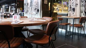 Een restaurantinterieur met ronde tafels, bruine lederen stoelen en wijnkannen op elk tafel.
