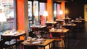 Un restaurant avec des tables et des chaises, éclairé par des lampes, et doté de grandes fenêtres.