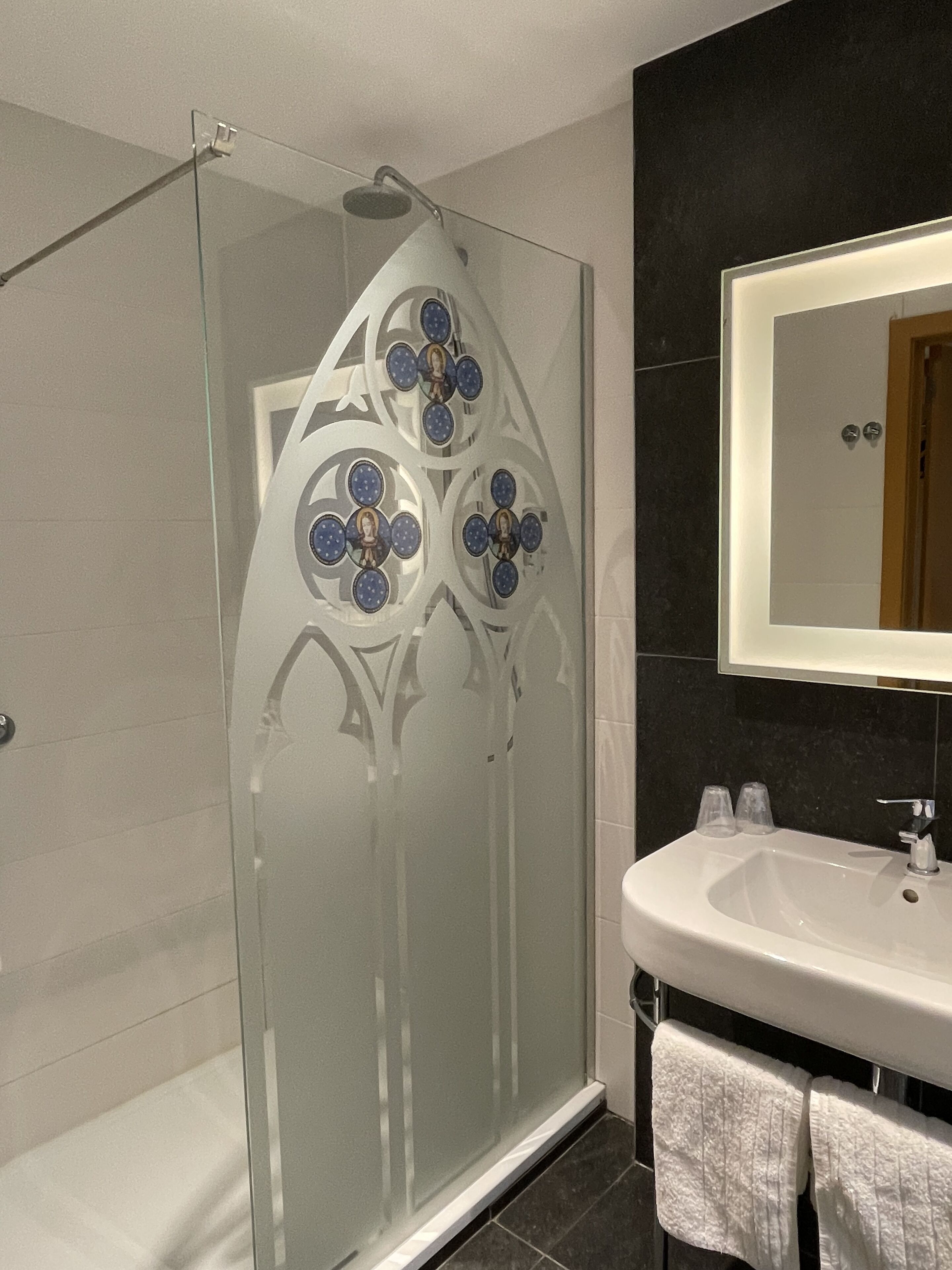 Un baño moderno con cabina de ducha de vidrio, un lavamanos blanco y un espejo encima.
