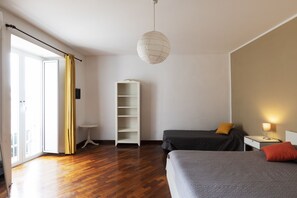 A hotel room with two beds, a white wardrobe, a small table, and a hanging light fixture. - B&B Museum (Naples)