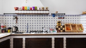 Une cuisine avec un dosseret carrelé, des armoires en bois, une cuisinière à gaz et divers ustensiles et appareils de cuisine.