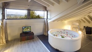 A modern bathroom with a large bathtub, a television, and a view of the countryside through a large window. - La Posada de Langre (Ribamontan al Mar)