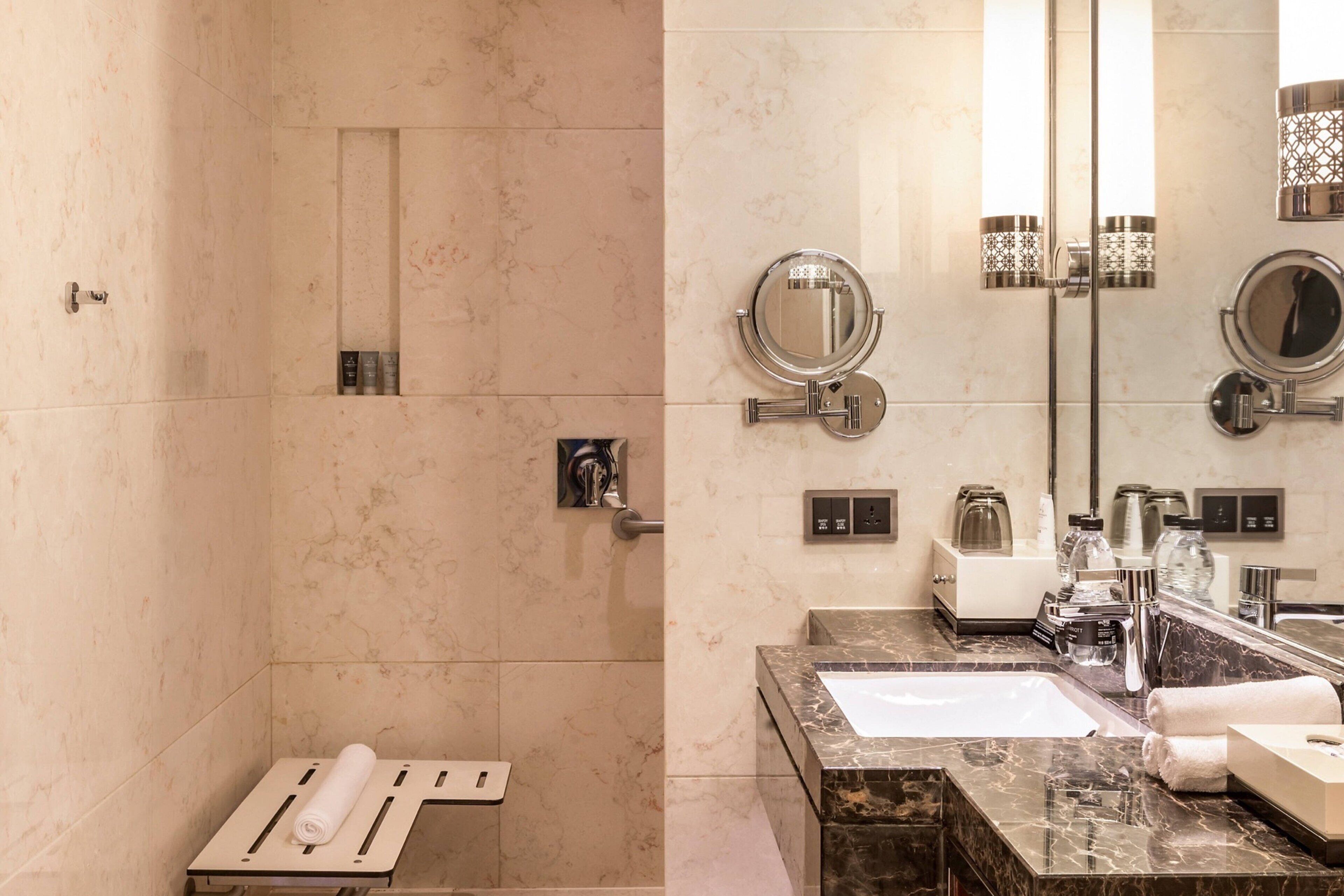 A modern bathroom with a shower, a sink with a marble countertop, and two wall-mounted mirrors.