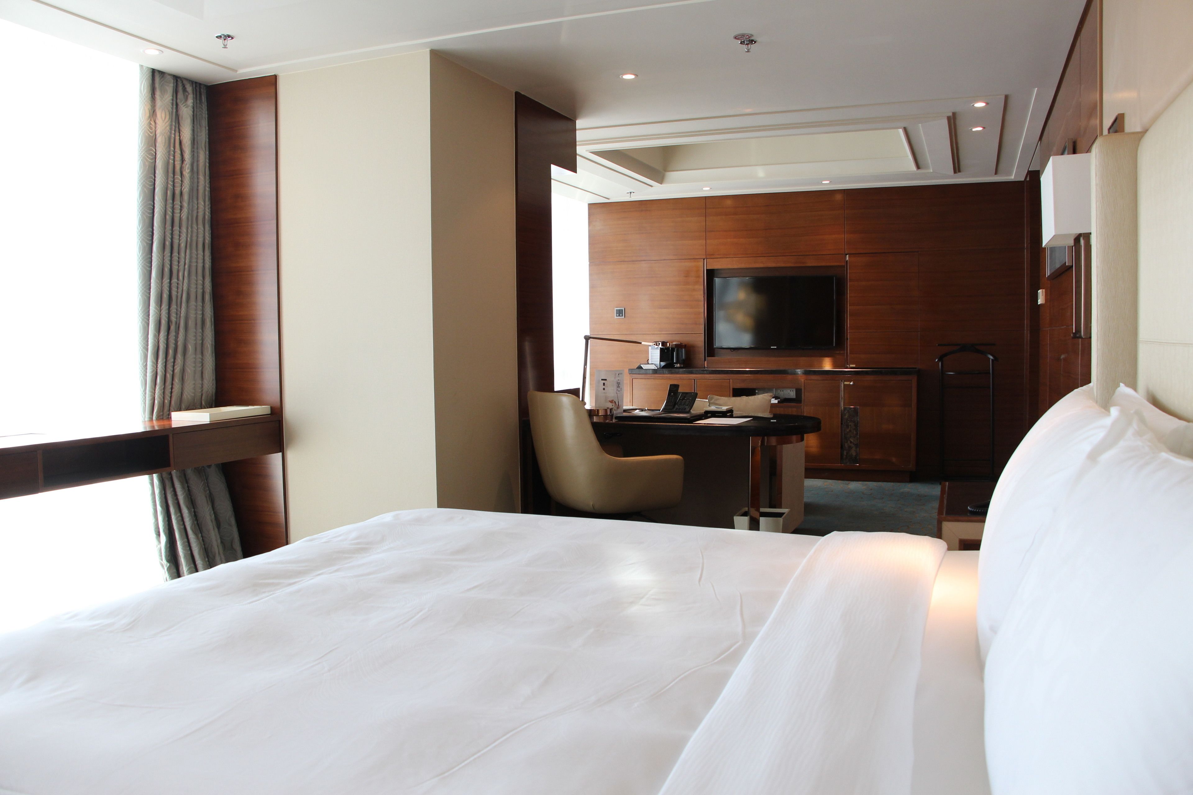 Een hotelkamer met een groot bed, een bureau met stoel, een televisie en een minibar.