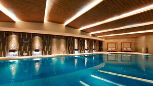 Una piscina interior moderna con techo de madera y suelo de baldosas.