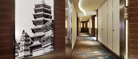 A hallway with a framed black and white photo of a pagoda, wooden paneling, and a patterned carpet.