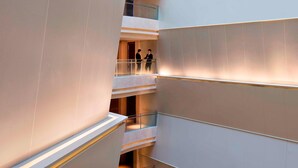 Un interior de varios niveles con un diseño moderno, que presenta una escalera central y barandillas de vidrio.