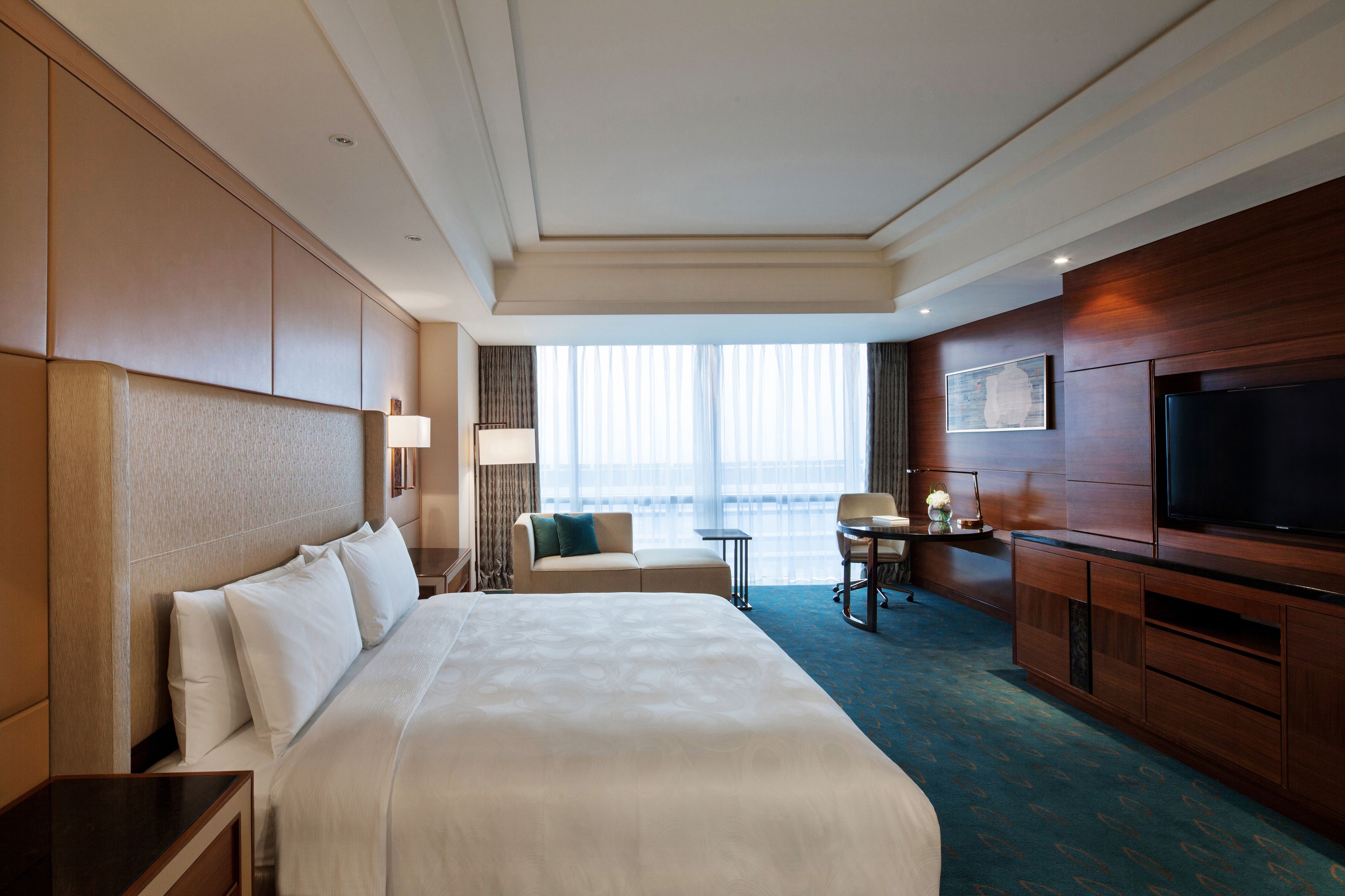 Habitación de hotel con una cama grande, un escritorio, un televisor y vista al océano.