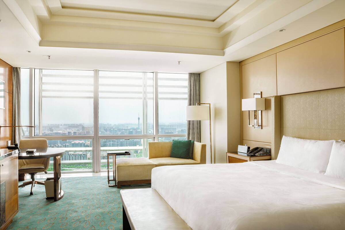 Une chambre d’hôtel avec un grand lit, un bureau, une chaise, une petite table et un canapé.