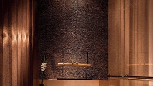 Un moderno cuarto de spa con una bañera grande, velas y una pared con textura.