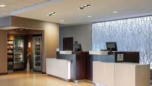 A reception area with a counter, a refrigerator stocked with snacks, and a wall with a tree pattern. - Fairfield Inn & Suites Springfield Northampton/Amherst (Northampton)