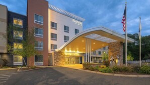 A Fairfield by Marriott hotel with a modern entrance, American flags, and a stone facade. - Fairfield Inn & Suites Springfield Northampton/Amherst (Northampton)
