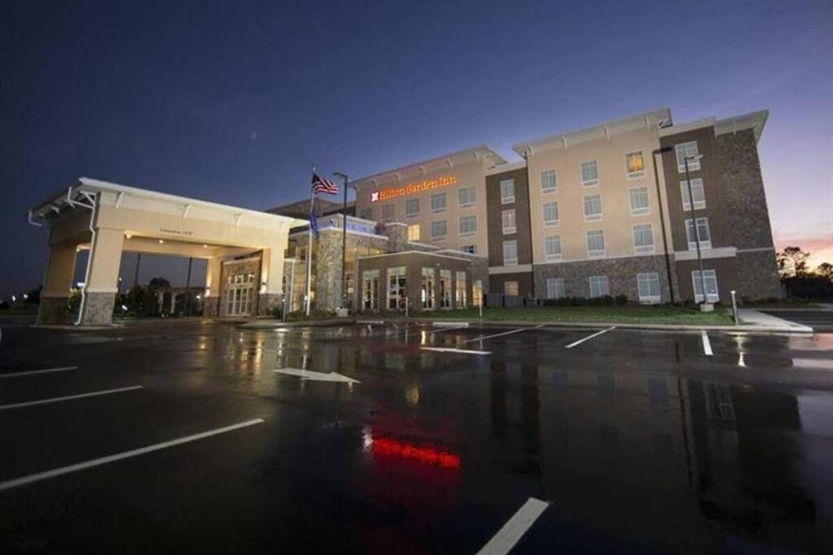 A hotel with a large parking lot, a covered entrance, and a prominent sign.