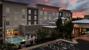 A Hilton Garden Inn with a swimming pool, parking lot, and a stone facade. - Hilton Garden Inn Murfreesboro (Murfreesboro)