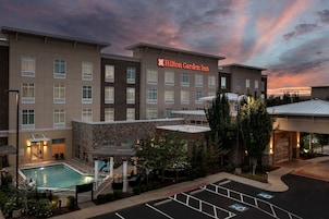 Un Hilton Garden Inn con piscina, estacionamiento y fachada de piedra.