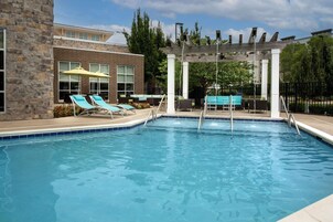 Una piscina con sillones de descanso y una pérgola.