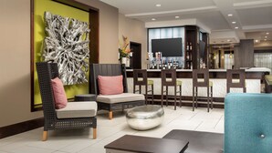 A modern lounge area with seating, a bar, and a large abstract art piece on the wall. - Hilton Garden Inn Murfreesboro (Murfreesboro)