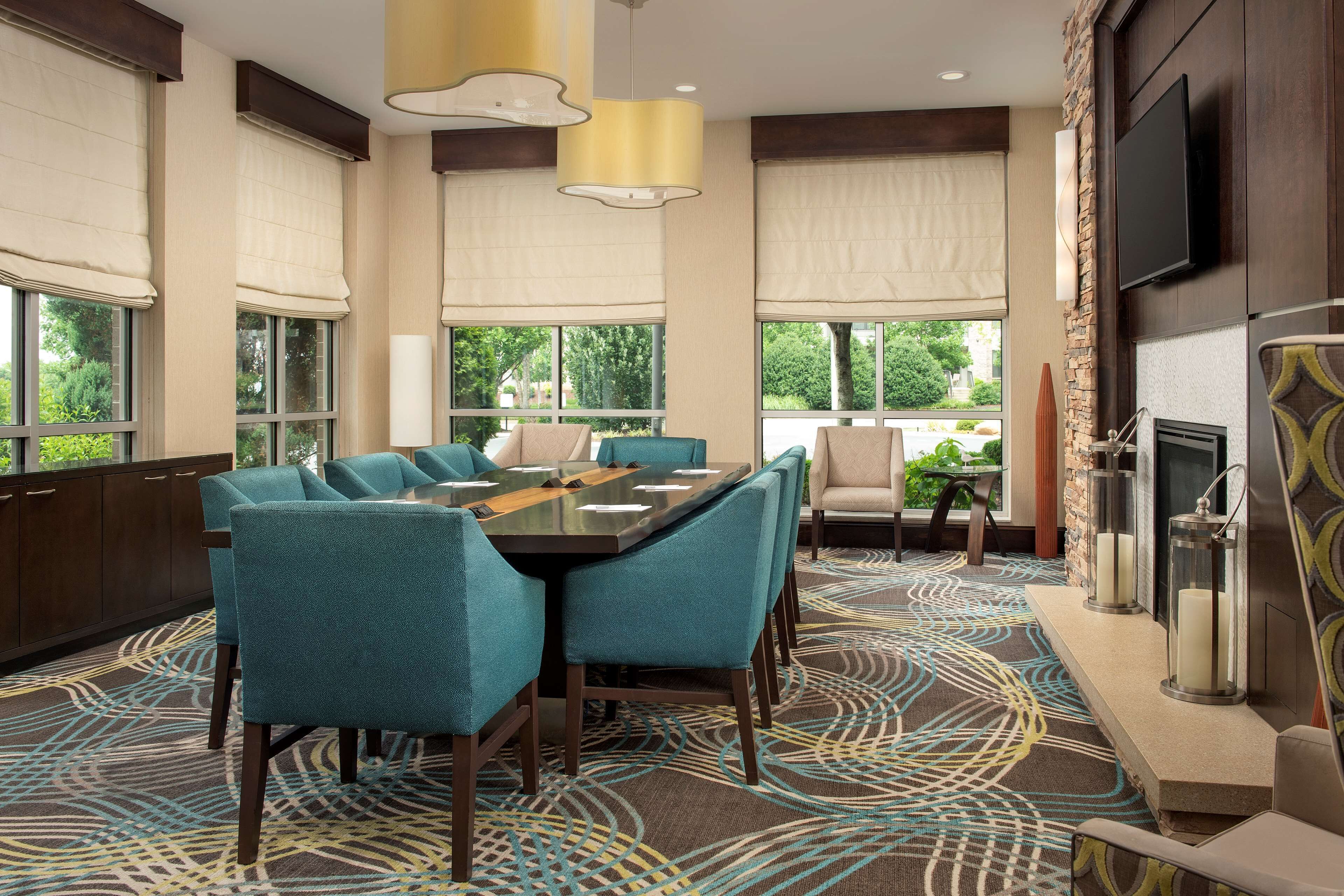 A conference room with a large table, teal chairs, and a patterned carpet.