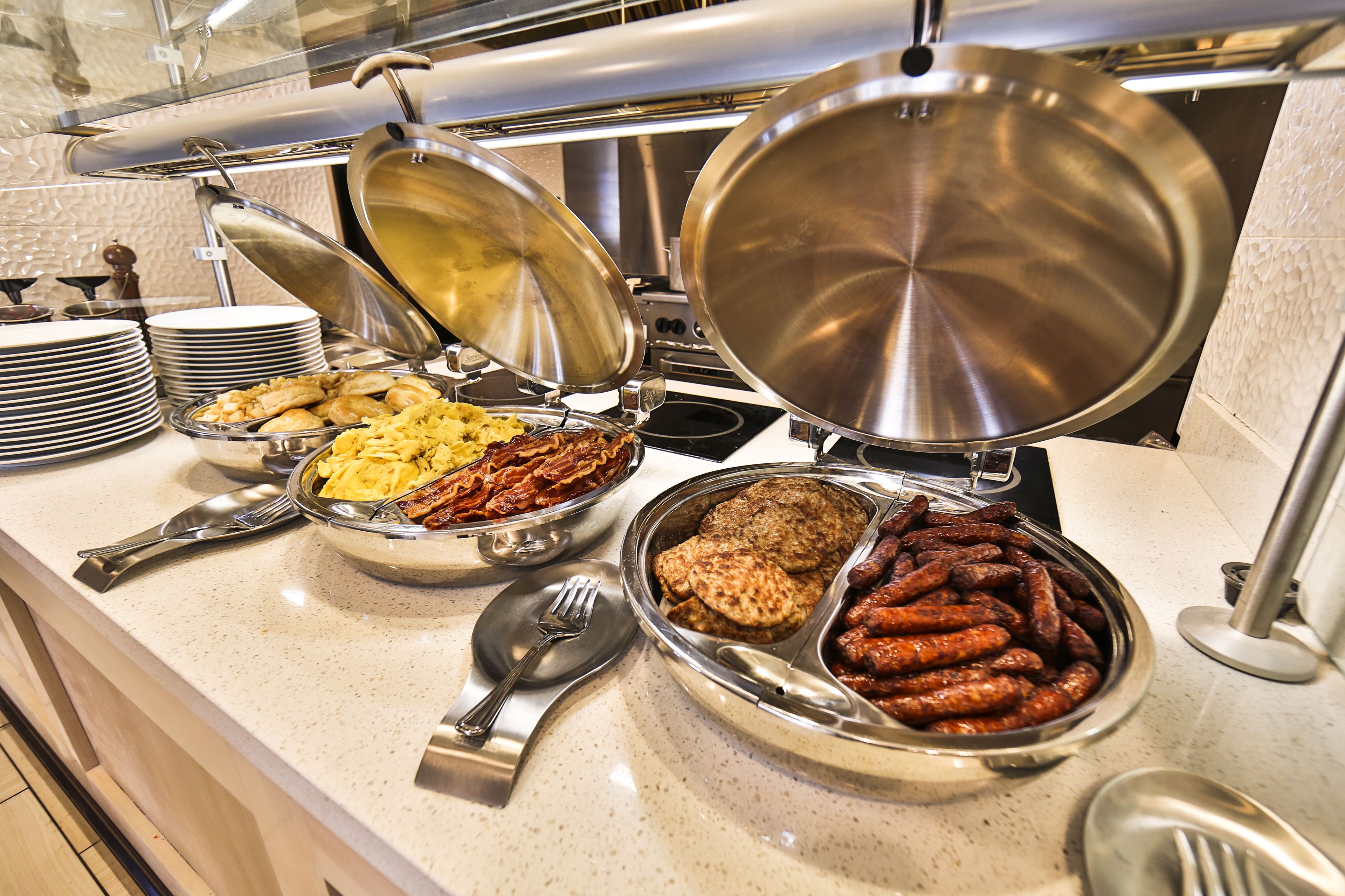 A buffet with various dishes including meats, eggs, and baked items.