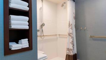 Un baño con inodoro, ducha con puerta de cristal y un perchero con toallas dobladas.