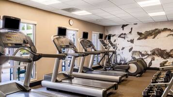 A gym with treadmills, weight machines, and a wall clock.