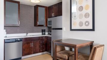 A modern kitchen with dark wooden cabinets, stainless steel appliances, and a dining area with a wooden table and chairs.