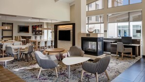 A spacious lobby with a fireplace, multiple seating areas, and large windows providing natural light. - Residence Inn Bloomington (Bloomington)
