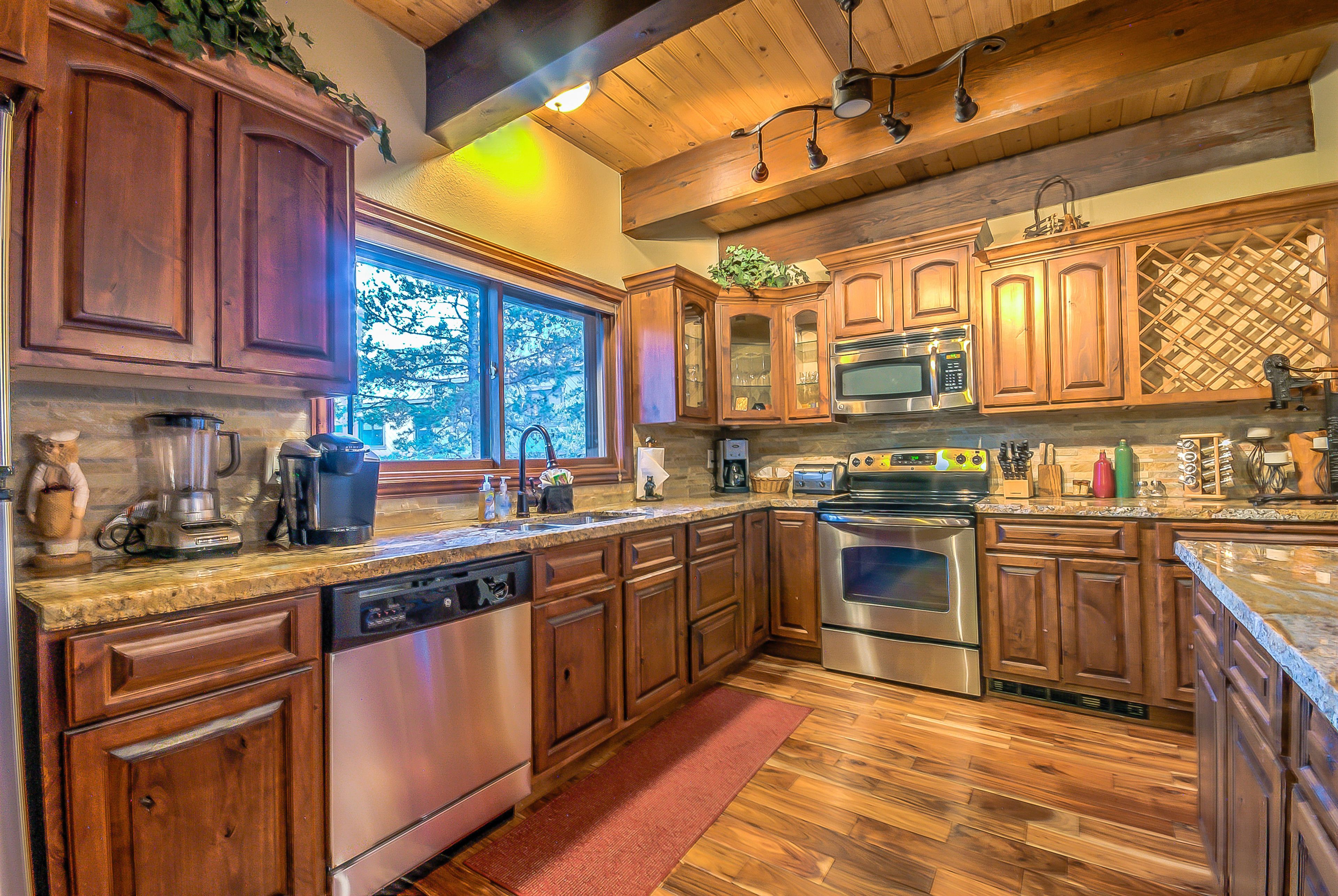 A kitchen with wooden cabinets, stainless steel appliances, and a large window.