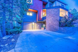 Een modern huis met twee verdiepingen, een garage, een gevel van baksteen en een verzorgde voortuin.