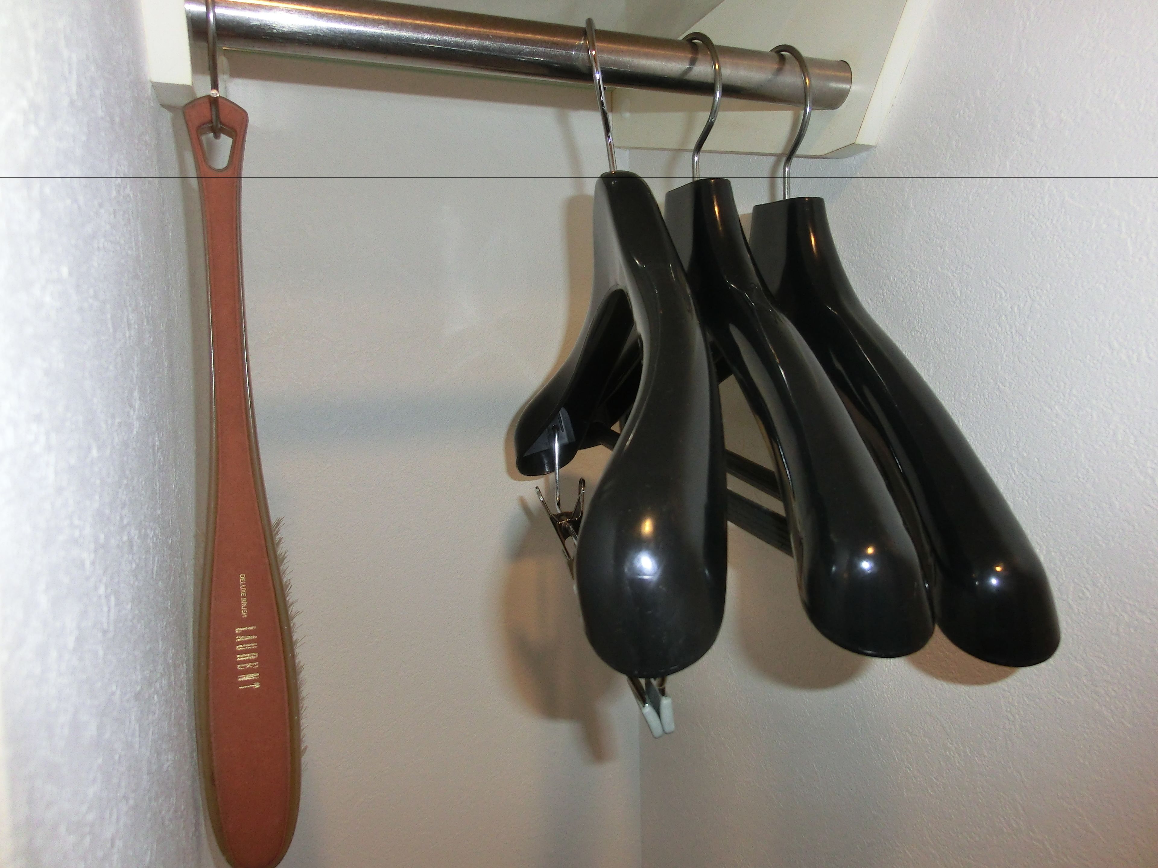 A metal rod with a wooden handle and a pair of black shoes hanging from it.