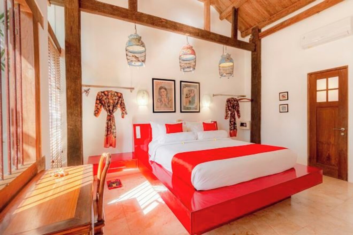 Un dormitorio con una cama grande, vigas de madera y lámparas colgantes.