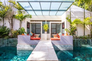A pool area with two seating areas, a glass ceiling, and surrounding greenery. - Bali Ginger Suites & Villa (Seminyak)