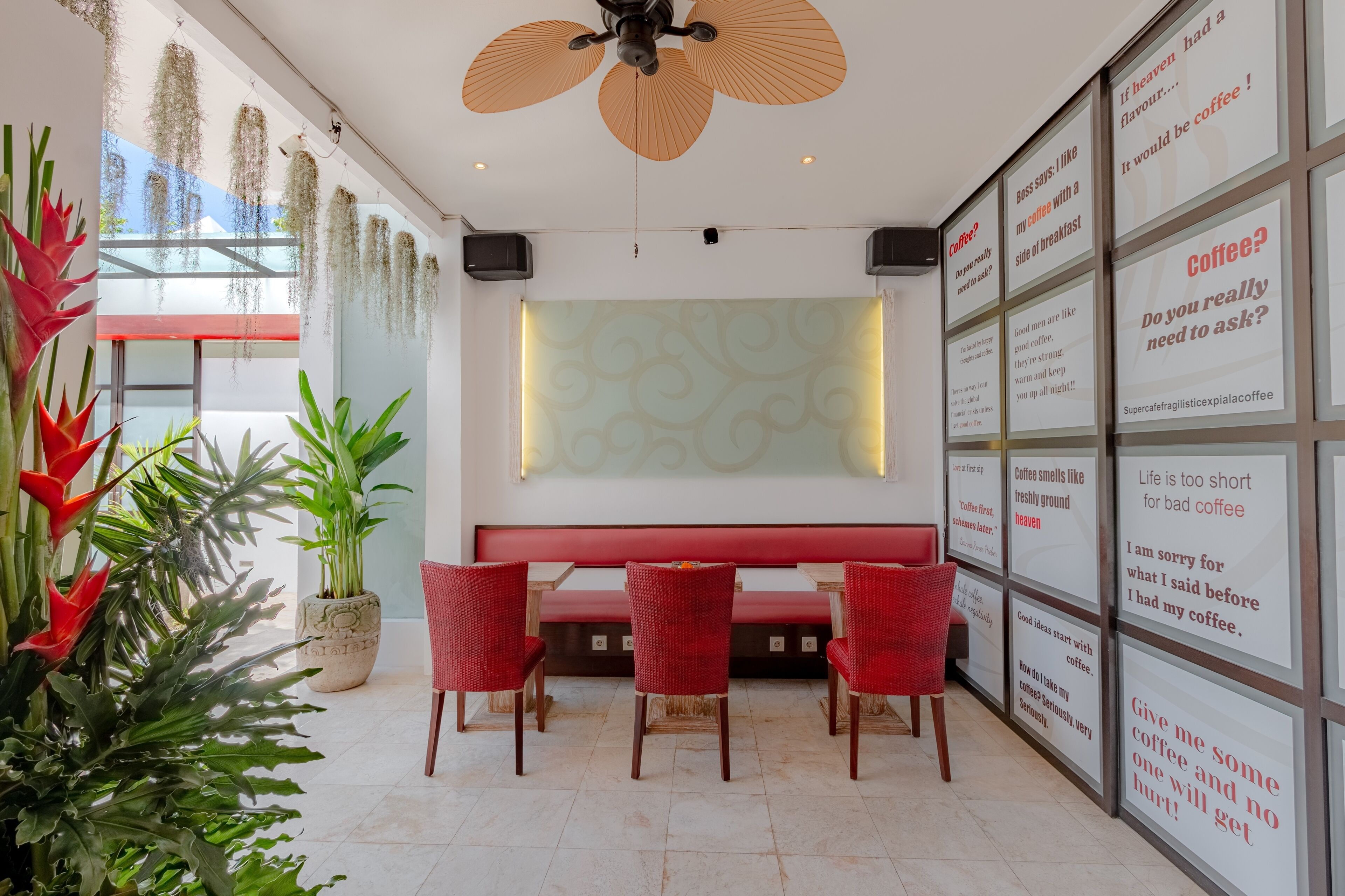 Ein modernes Interieur mit einer roten Bank, roten Stühlen und einem Deckenventilator.