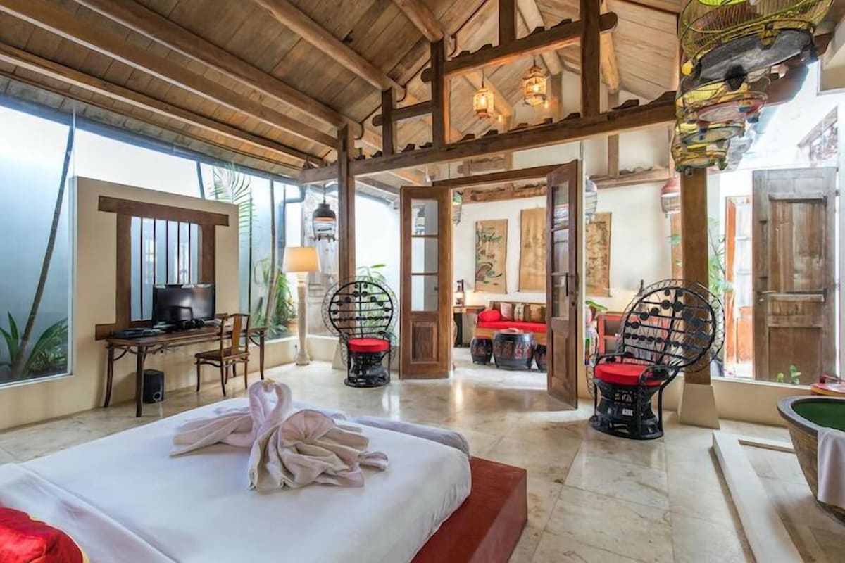 Une chambre d’hôtel avec un lit, deux chaises, un bureau et un téléviseur.