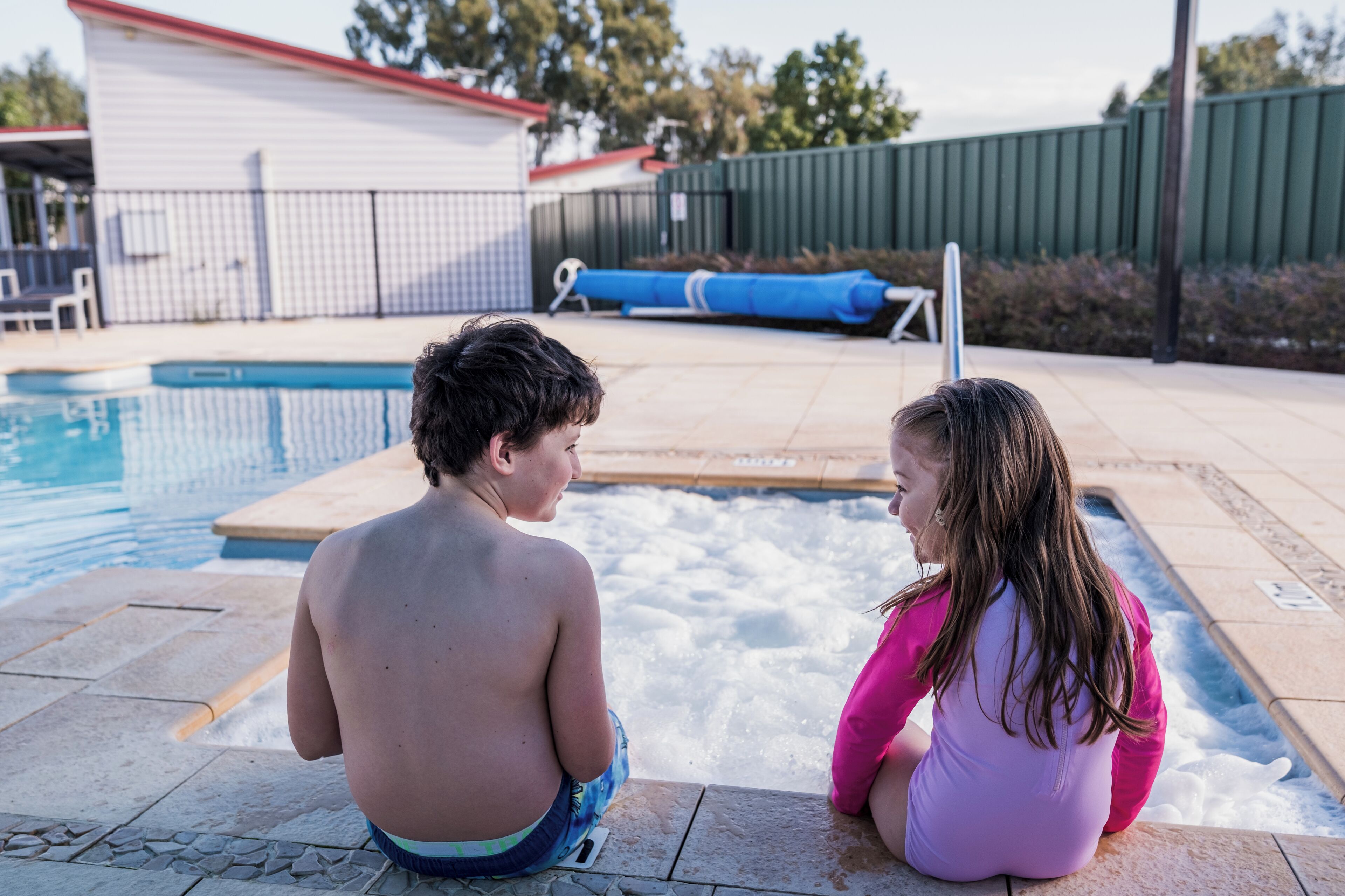 Una piscina con muelle de madera y un área cercada al fondo.