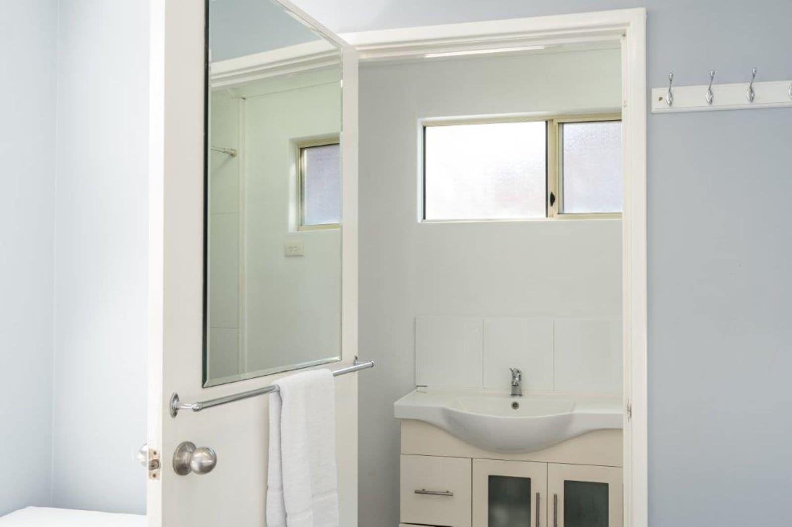 A bathroom with a white sink, a mirror, and a towel rack.