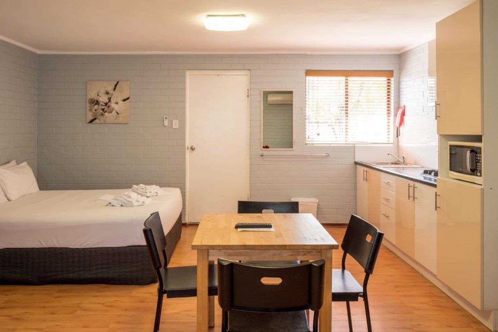 A compact room with a bed, a small table, and a kitchenette.