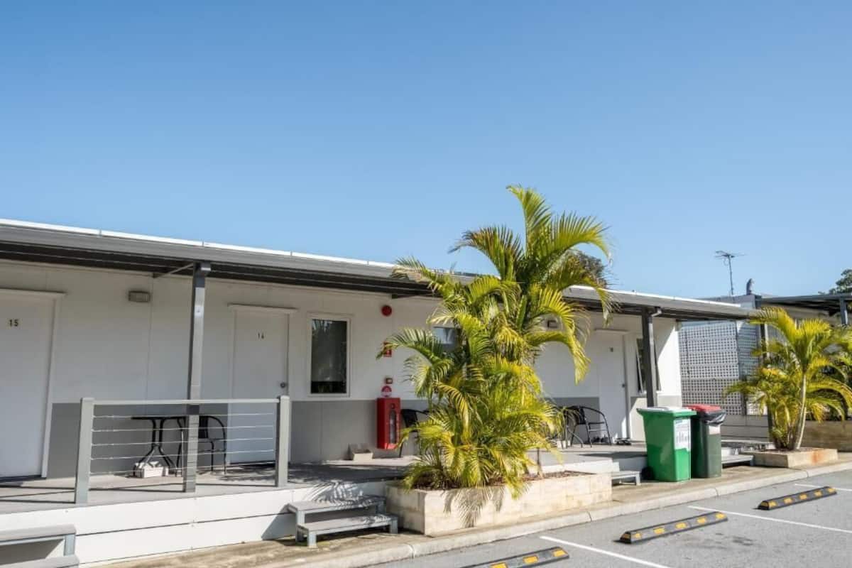 A building with numbered doors, outdoor seating, and palm trees.